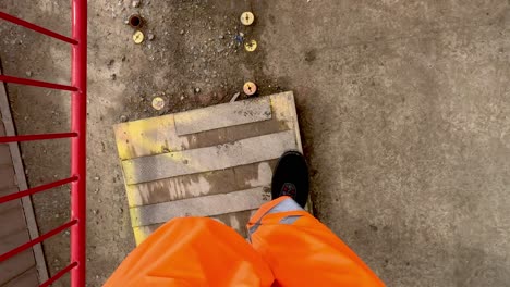 POV-Of-Feet-Walking-Wearing-Bright-Orange-High-Visibility-Trousers-At-Construction-Site
