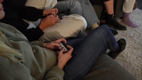 group of friends sat on couch playing on games console