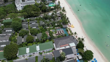 modern vacation holiday homes beach houses lined up in perfect system neighbourhood layers next to each other grey and green roofs pools garden covered trees in between pure clean water ocean sea hot