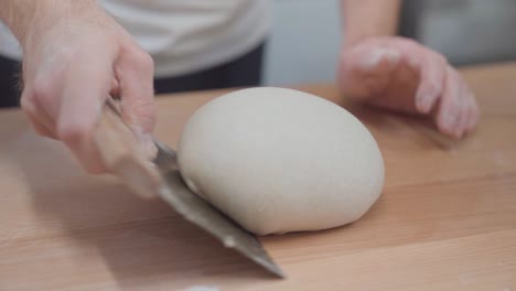 chef using dough scraper to form a loaf of bread out of dough