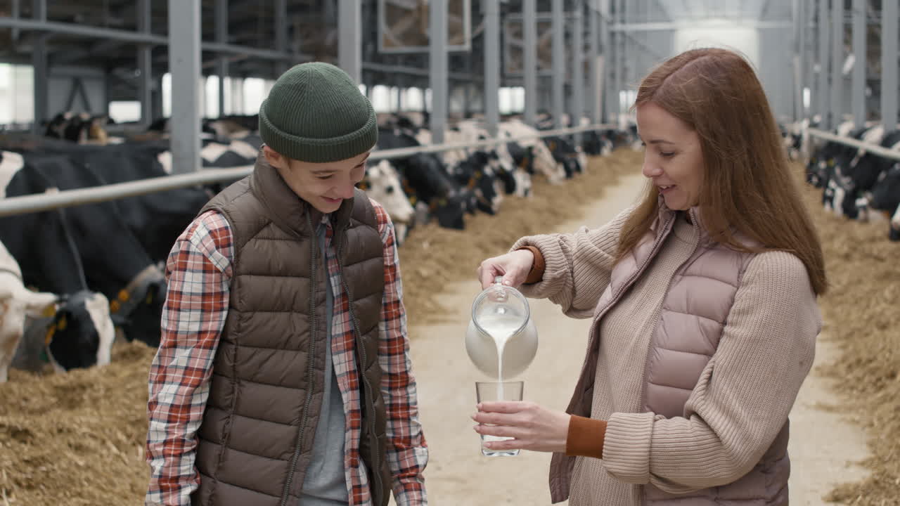 Woman Pouring Fresh Milk for Teenage Boy at Farm