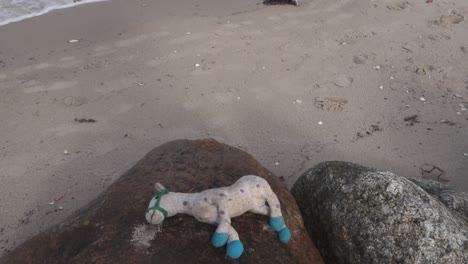 juguete infantil olvidado dejado en la roca en la playa, tiro inclinado