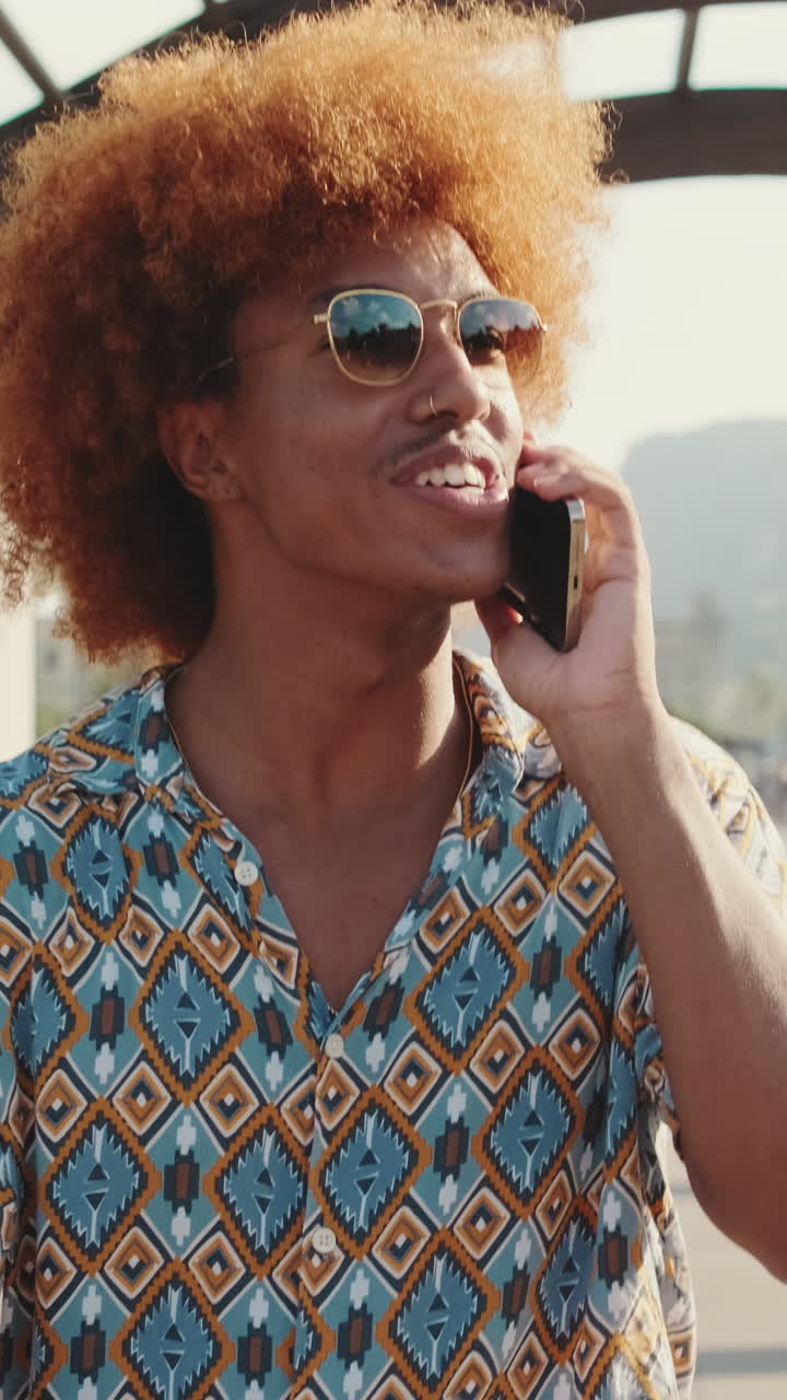 Young Man with Curly Red Hair Talking on Smartphone and Smiling