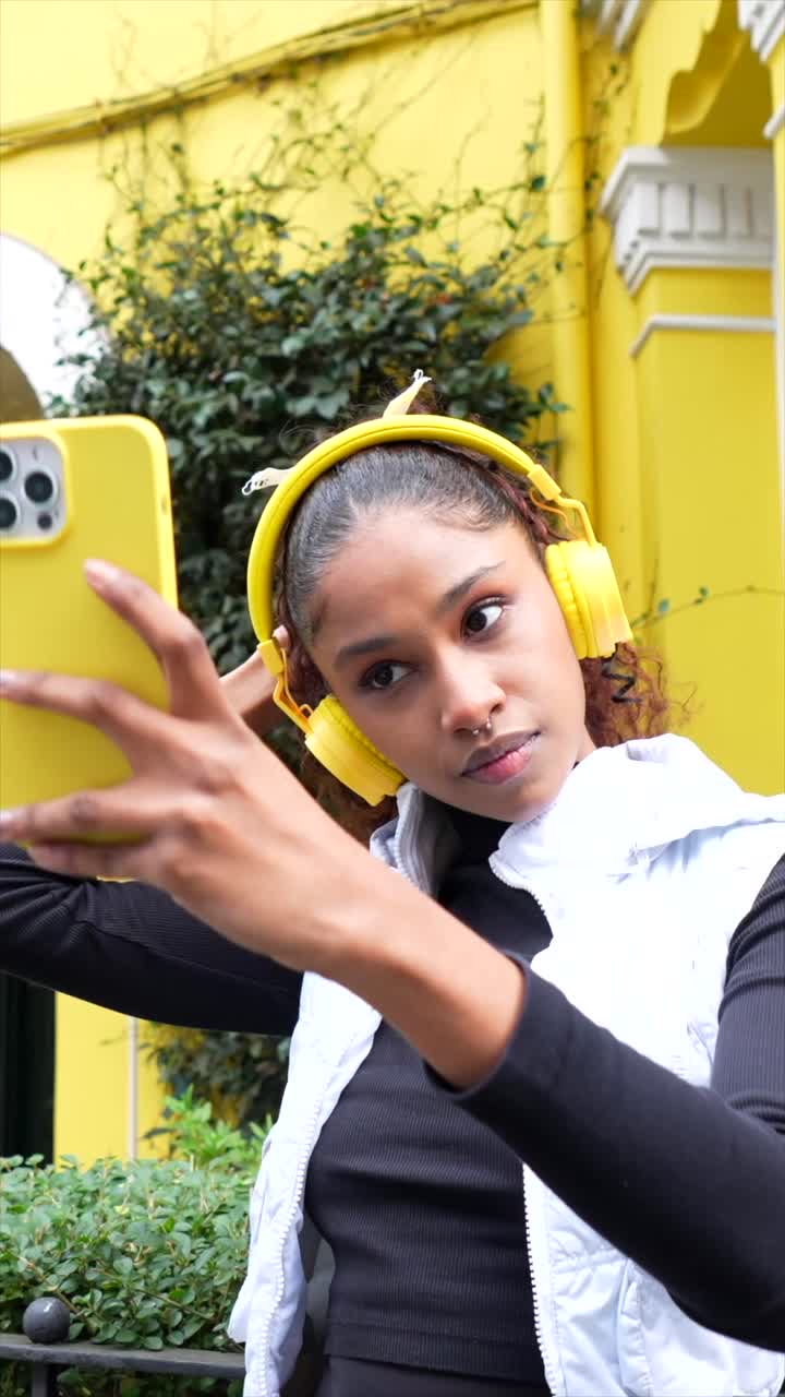 Woman taking selfie with yellow phone and headphones