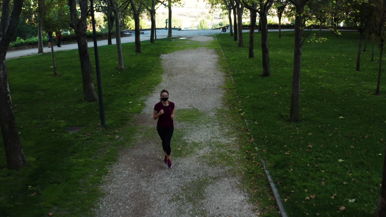 Birdseye aerial shot of a woman in mask jogging in Tierno Galván Park