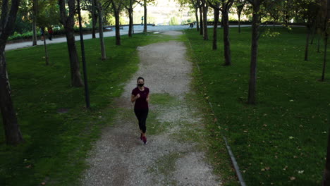 Birdseye-aerial-shot-of-a-woman-in-mask-jogging-in-Tierno-Galván-Park