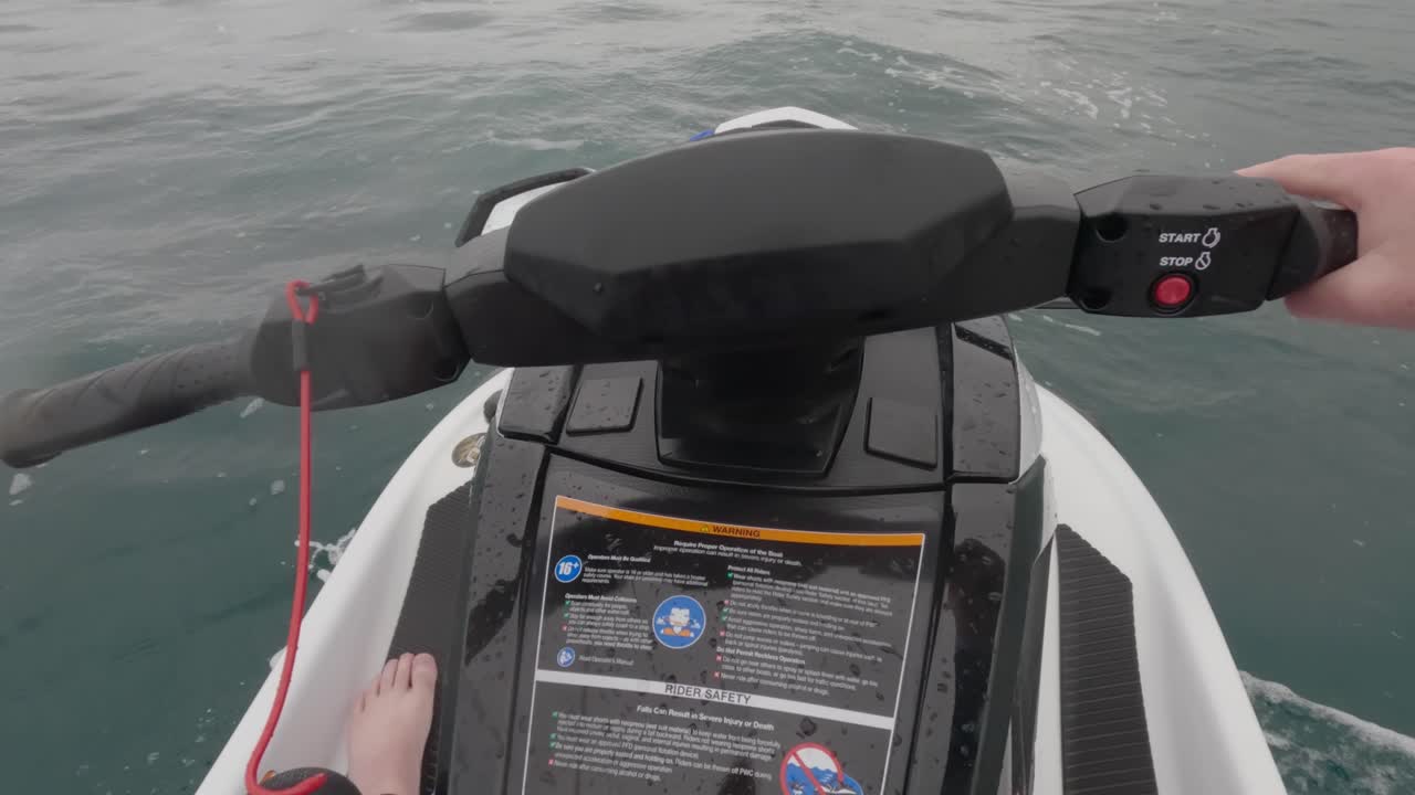 Rekaman POV seorang pengendara jet ski yang melaju perlahan melintasi lautan sambil menunjukkan sakelar pemutus.