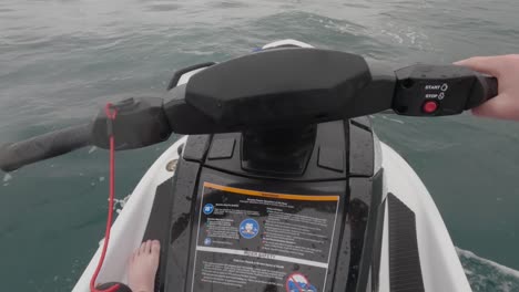 una foto de un piloto de jet ski conduciendo lentamente a través del océano mostrando el interruptor de muerte