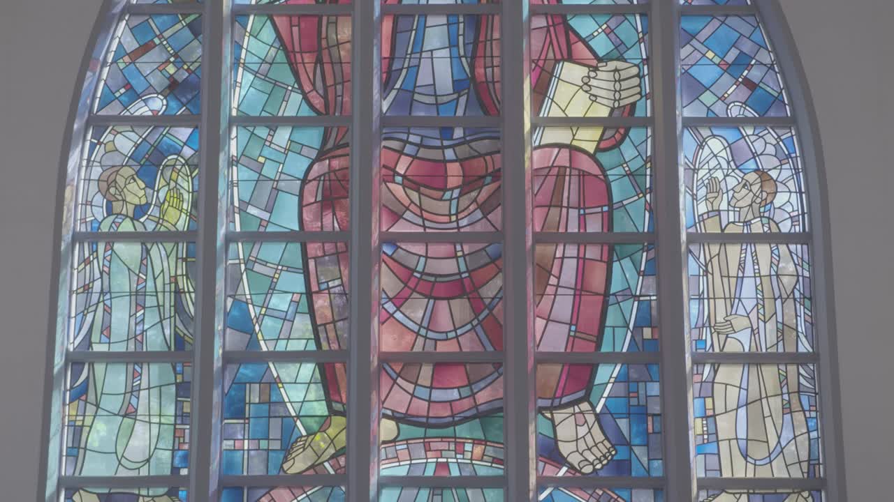 Camera panning along a large and colorful window in a church