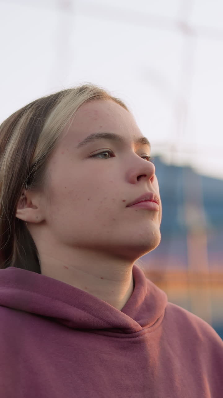 primer plano de una dama saltando y jugando al voleibol, alcanzando para golpear la pelota sobre la red, el fondo presenta edificios y árboles borrosos. manos y brazos en foco