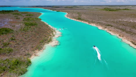 Filmische-Jagende-Drohnenaufnahme-Von-Jet-Skifahrern-Und-Klarem-Blauem-Wasser-In-Bacalar-Mexiko