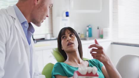 dentista caucásico examinando los dientes de una paciente en una clínica dental moderna