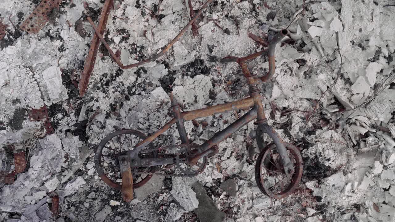 불탄 아파트 단지의 잿더미 한가운데 버려진 어린이 세발자전거 - 산불 여파 - 4k
