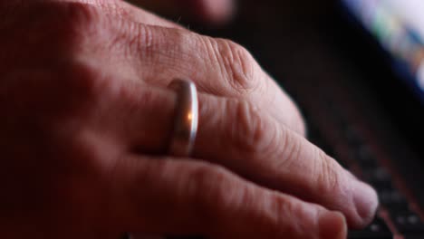 close-up of side view with bokeh man's hands typing on a laptop backlit by the screen