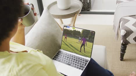 Afroamerikanische-Frau-Benutzt-Laptop-Mit-Verschiedenen-Männlichen-Fußballspielern,-Die-Auf-Dem-Bildschirm-Ein-Spiel-Spielen