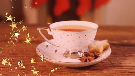 Animation-of-glowing-stars-falling-over-cup-of-tea-with-christmas-cookies