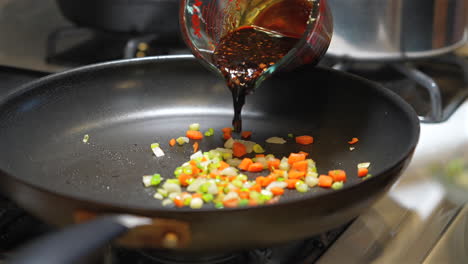 adding japanese sauce to the diced vegetables to sauté in a pan - slow motion