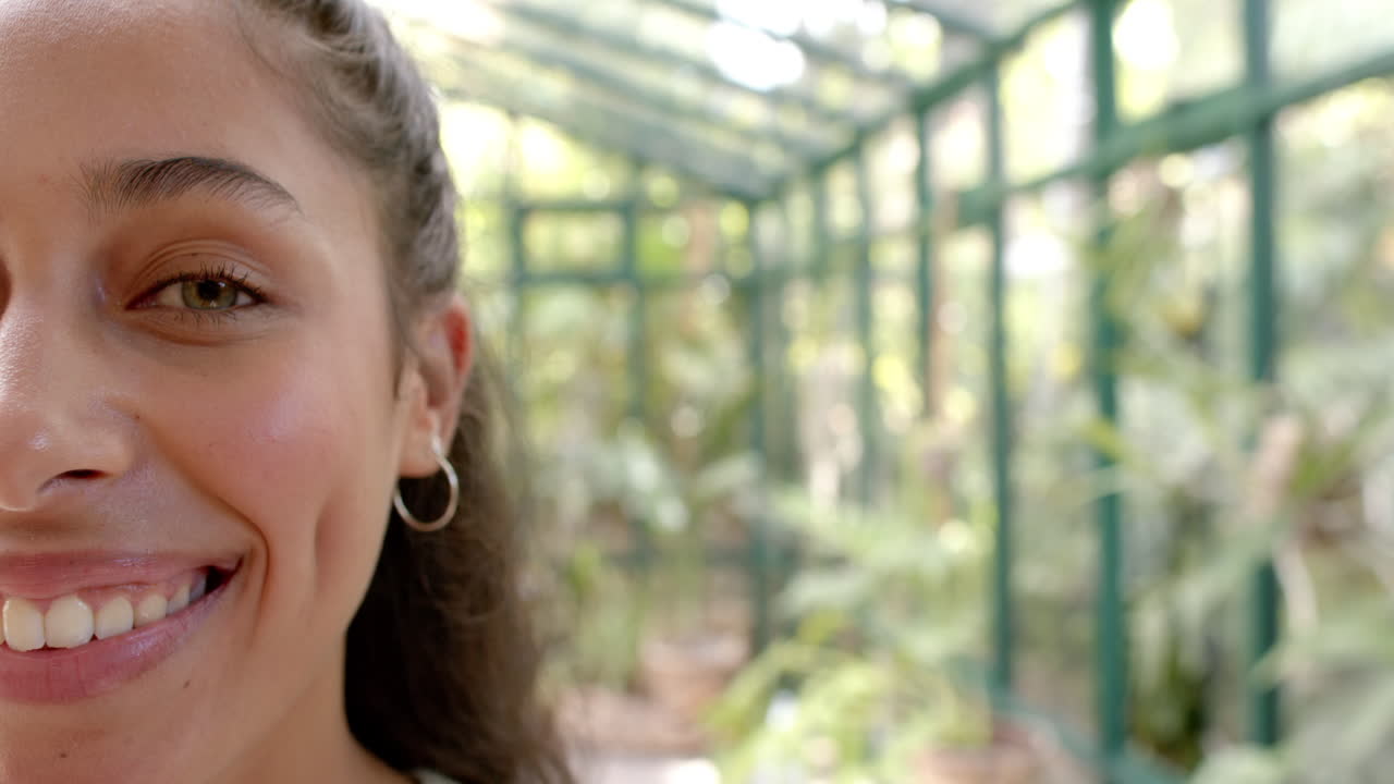 Smiling woman with hoop earring in glass house, enjoying peaceful surroundings, copy space