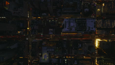 Aerial-birds-eye-overhead-top-down-panning-view-of-evening-city.-Fly-above-illuminated-streets-and-blocks-of-high-rise-buildings.-Manhattan,-New-York-City,-USA