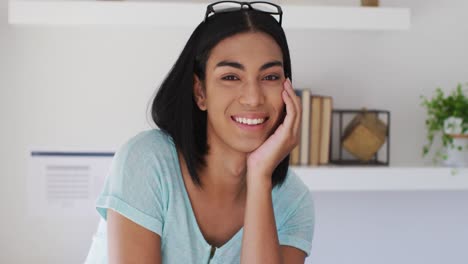 retrato de una persona de género fluido de raza mixta mirando a la cámara y sonriendo en casa