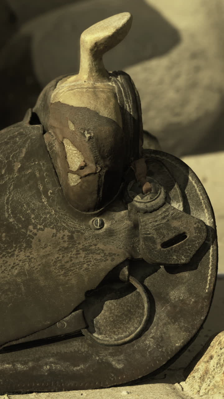 Old leather saddle resting on rocky beach amidst quiet landscape