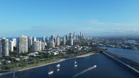 unique high drone view of a gold coast skyline surrounded by water with a tram and motor vehicle bridge spanning over a city river system