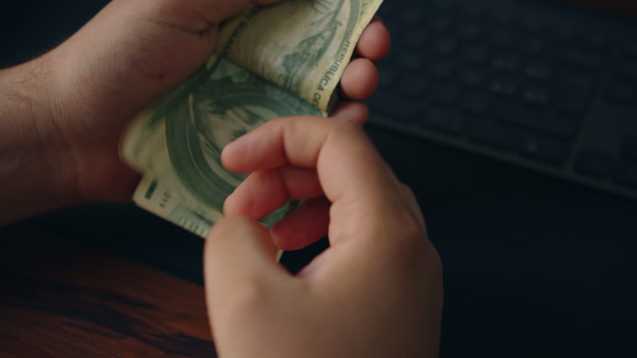 Close-up van mannenhanden die een stapel van honderdduizend Guaraní PYG bankbiljetten tellen op een tafel