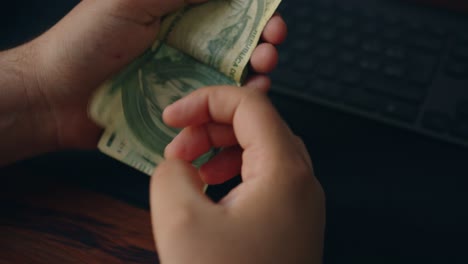 primer plano de manos masculinas contando una pila de cien mil billetes de guaraní en una mesa