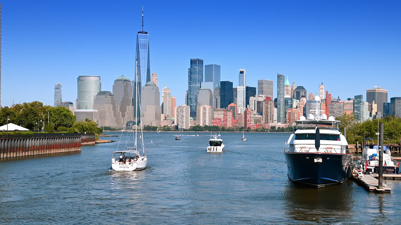 Clear day sailing NYC harbor. Boats navigate the Hudson River as the New York City skyline shines under a bright blue sky