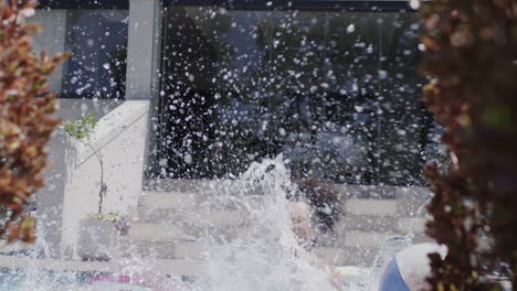 happy african american mother and daughter jumping into swimming pool, slow motion