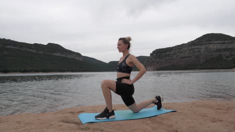 colocar mujeres estirando su pierna izquierda al lado de un lago