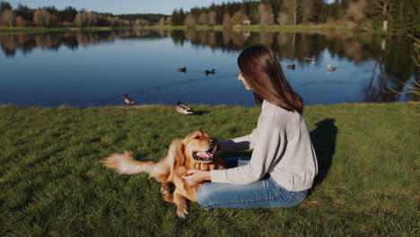 woman petting a golden retriever by a lake