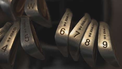 close-up shot of a 6 iron being added back into a golf bag beside other clubs