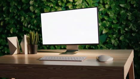 modern computer monitor mockup on wooden desk with green plant wall background