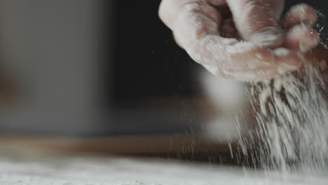 hand sprinkling flour on table