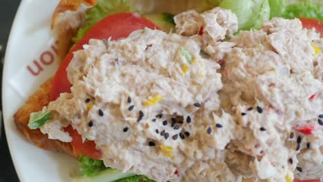 primer plano de un sándwich de croissant de atún con tomate y lechuga