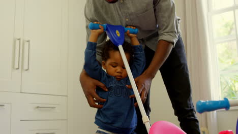 front view of cute little black kid playing with tricycle in a comfortable home 4k