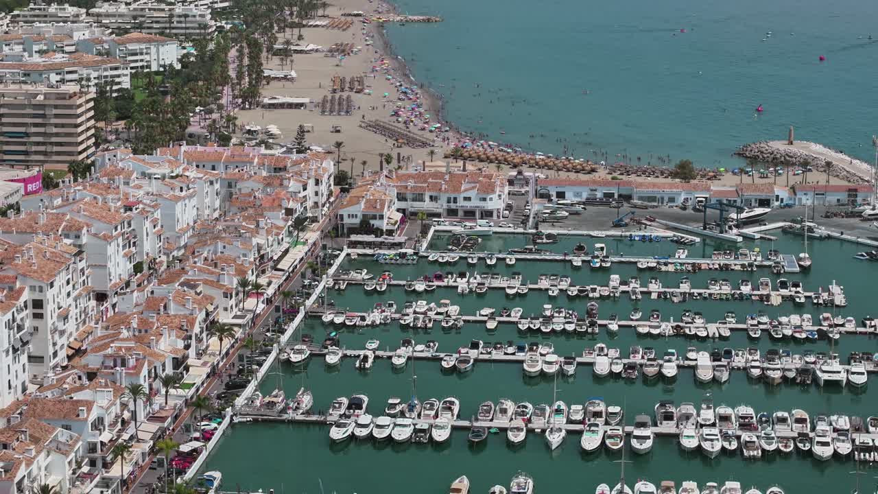 aerial view of Marbella marina with boats and crowded beach Spain