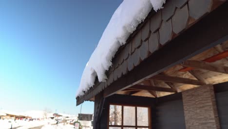 Tilt-down-detail-view-of-snow-on-a-wooden-roof-of-a-bus-stop-in-the-mountain-village-of-Farellones,-Chile