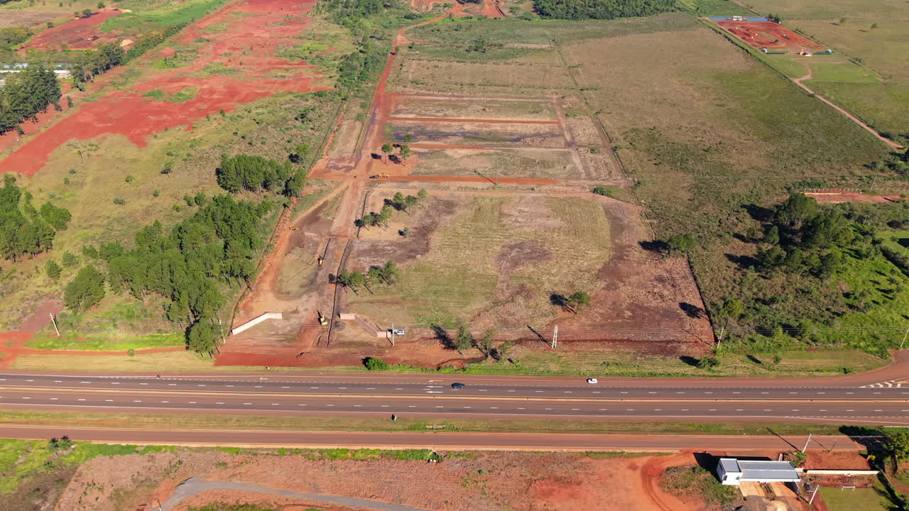 Construction site with red soil near highway in argentina, clear day, aerial view