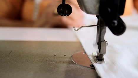 Tracking-shot-close-up-of-a-sewing-machine-operated-by-a-tailor