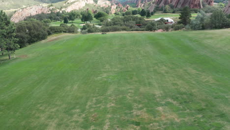 campo de golf de punta de flecha en littleton colorado con césped verde, rocas rojas y cielos azules
