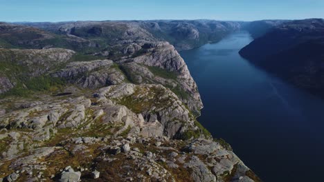 sunlit aerial view of preikestolen with fjord and peaks in the background, capturing norway’s beauty.