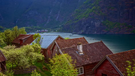 casas tradicionales noruegas a orillas del fiordo aurlandsfjord con crucero pasando en segundo plano