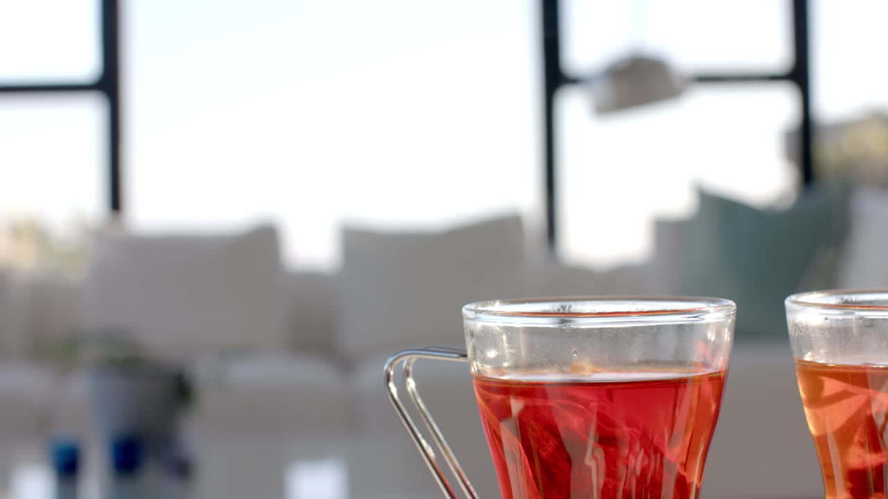Close-up of two glasses of tea on table in bright living room, copy space