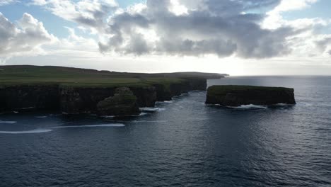 rugged-cliffs-against-the-ocean-under-a-cloudy-sky-at-dusk,-showcasing-nature's-grandeur