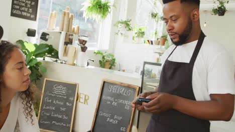 Feliz-Clienta-Birracial-Pagando-El-Pedido-Con-Un-Teléfono-Inteligente-En-La-Cafetería