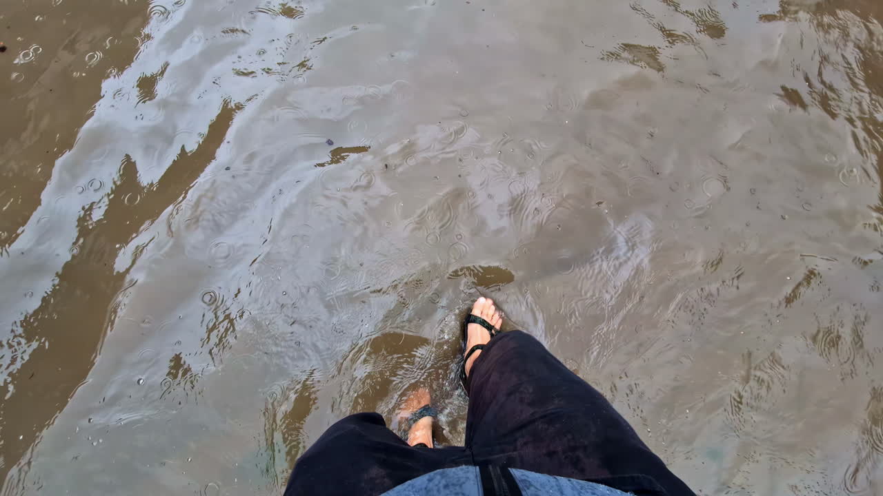 A lone man wades through deep floodwaters in a city, showcasing the scale of urban flooding in Jelgava Latvia