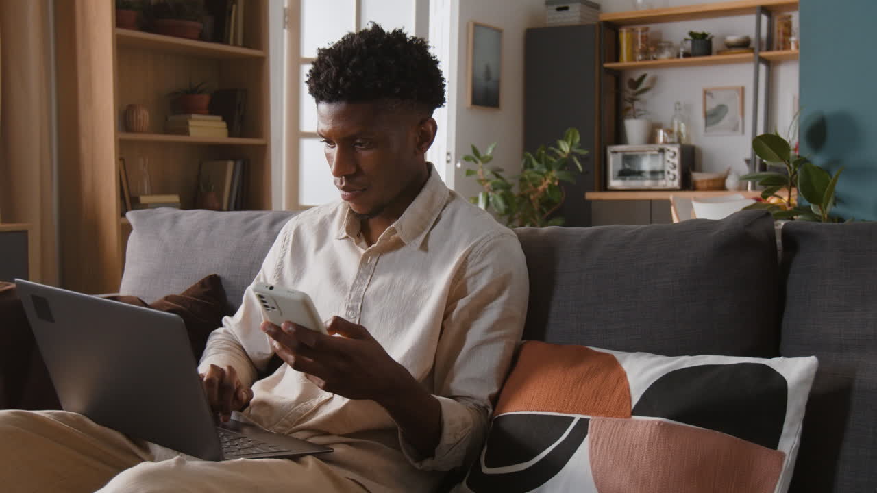 Man using laptop and phone on couch