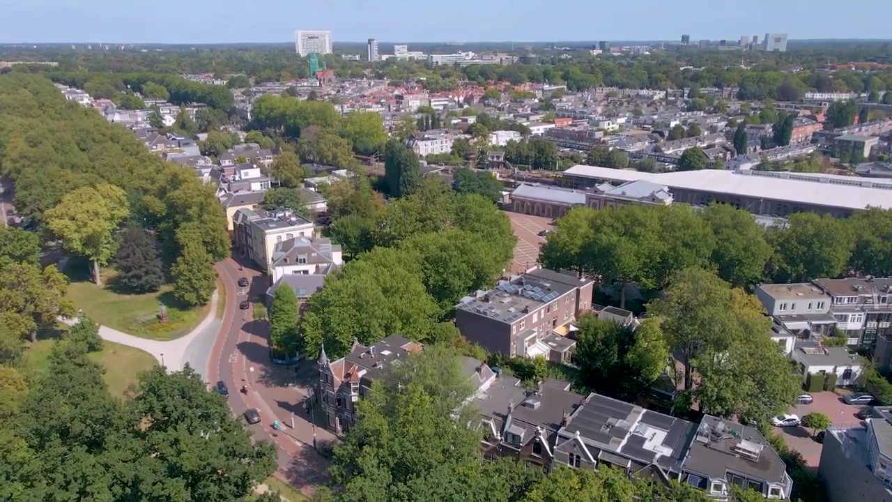 Vista aérea de drone de Utrecht, Países Baixos, apresentando sua torre de igreja histórica, edifícios com telhados vermelhos, horizonte moderno e paisagem urbana ensolarada que mistura arquitetura antiga e nova